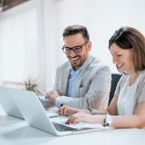 Mann und Frau sitzen an ihren Laptops