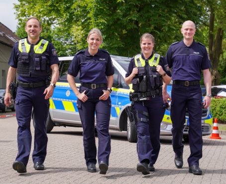 Polizistinnen und Polizisten präsentieren die neuen Poloshirts